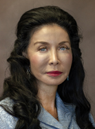 Portrait of a woman with long, dark hair wearing a gray top, looking directly at the camera against a neutral background.